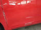 a close up of a red car with a denting on it