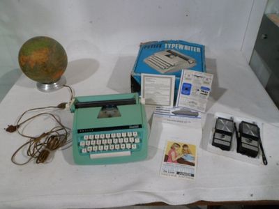 a green typewriter sitting on top of a table next to a globe