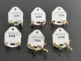 six pairs of earrings with price tags on them sitting on a table