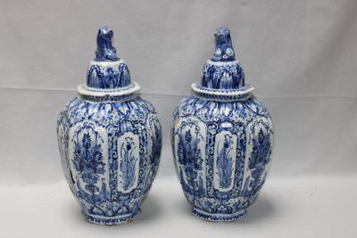 Deux vases bleus et blancs munis d'un couvercle sont posés sur une table.