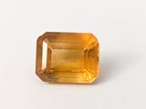 a close up of a yellow sapphire stone on a white surface