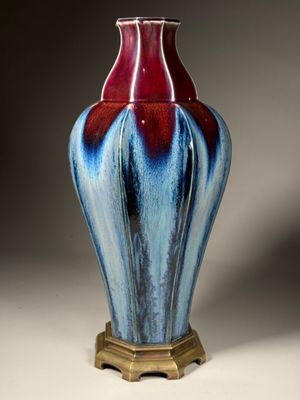 un vase bleu et rouge avec un socle doré