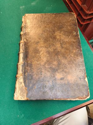 un vieux livre posé sur une table verte, à côté d'une pile de livres
