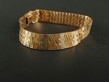 a gold bracelet that is on a black surface