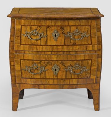 a wooden chest of drawers with metal decorations on the drawers