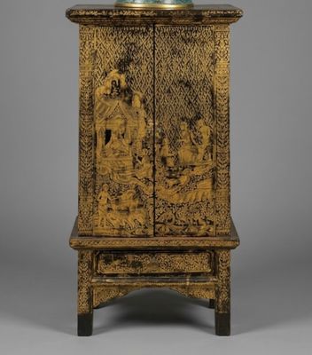 a chinese carved cabinet with two doors and a vase on top of it