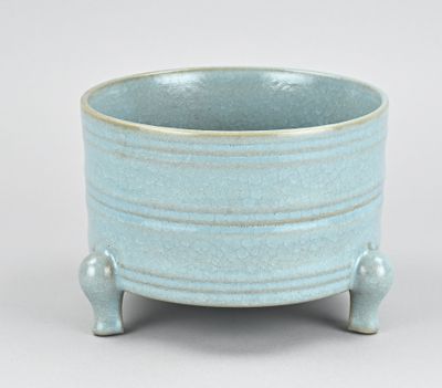 un petit bol bleu posé sur un socle, sur une surface blanche