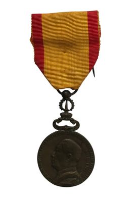 une vieille médaille ornée d'un ruban rouge et jaune sur fond blanc