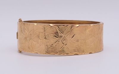 gros plan d'un bracelet en or sur une surface blanche
