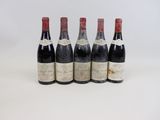 quatre bouteilles de vin sont alignées sur une surface blanche