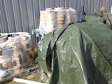 une bâche verte posée par terre à côté d'un tas de sacs