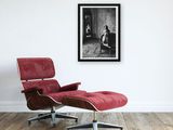 a picture of a woman sitting on a red chair in front of a picture of a man