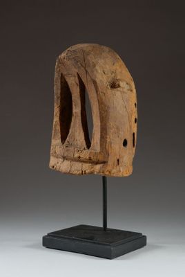 a wooden sculpture of a face on a black stand