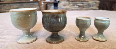 three cups sitting on a table with a stone wall in the background