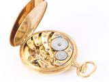 a gold pocket watch that is open on a white surface