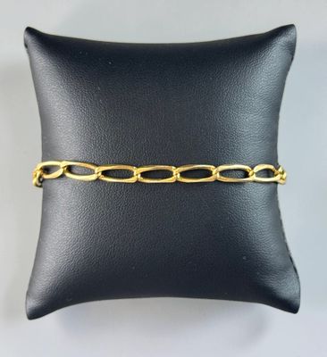 a black pillow with a gold chain bracelet on it