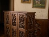 a wooden cabinet in the middle of a room with pictures on the wall