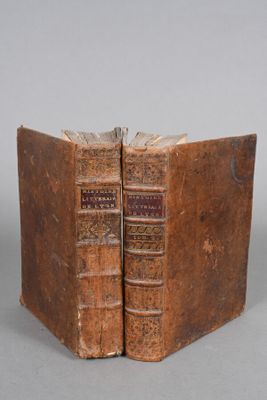 two old books sitting on top of each other on top of a table