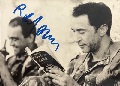 une vieille photo montrant un homme en train de lire un livre, avec un autre homme assis à côté de lui
