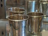 quatre tasses en argent posées sur une table en verre