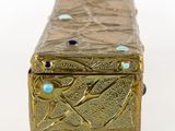 gold metal box with blue stones on top on a white surface