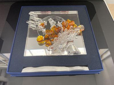 une sculpture en verre dans une boîte bleue posée sur une table