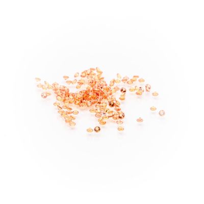 a pile of gold colored glass beads on a white background