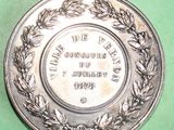 a silver plate with a wreath on it on a green surface