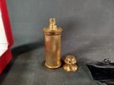 a small gold spray bottle next to a small red box