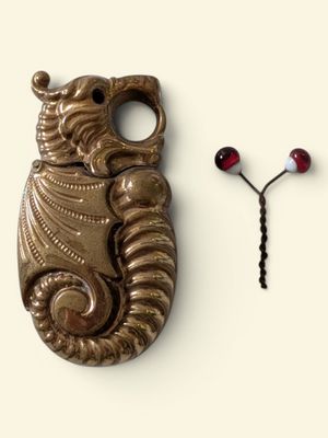 a metal object that looks like a seahorse and a bead