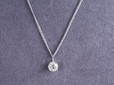 a woman wearing a necklace that has a diamond on it