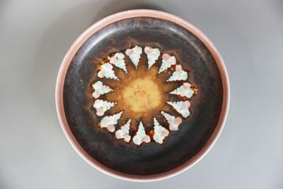 un bol marron avec des fleurs blanches à l'intérieur, posé sur une table