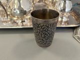 a silver cup sitting on a tray next to a tray of silverware
