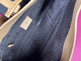 the inside of a black and tan handbag with a pink background