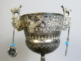 a silver vase with a peacock decoration on it
