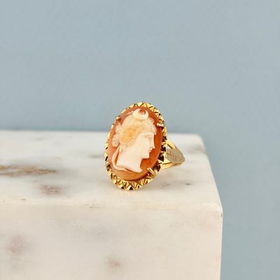un gros plan d'une bague en or sur laquelle est gravé le visage d'une femme