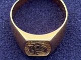 a close up of a gold signet ring on a blue carpet