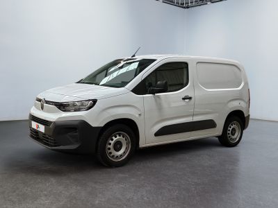 La camionnette blanche est garée dans une grande pièce blanche.