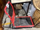 un diable rouge posé par terre à côté d'une chaise