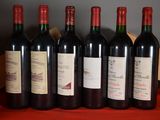 six bottles of red wine are lined up on a table