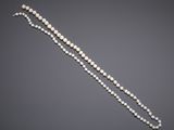 a white pearl necklace with a gold clasp on a gray background
