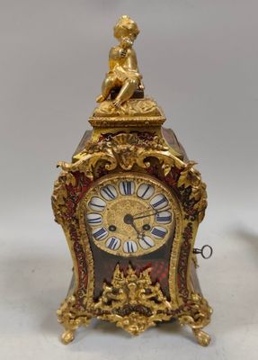 a gold clock with a statue on top of it