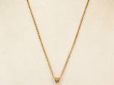 a gold necklace with a coin on a mannequin neck