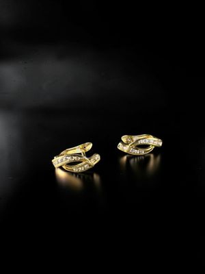a pair of gold earrings with diamonds on a black background