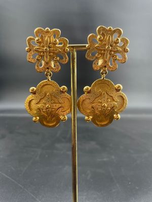 une paire de boucles d'oreilles en or posée sur un présentoir