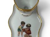 a small cup and saucer with a picture of a boy and a girl on it