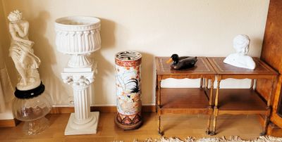 une petite table sur laquelle se trouve un vase, à côté d'une lampe