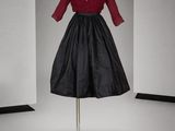 une robe noire et rouge posée sur un mannequin dans une pièce