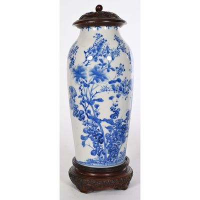 un grand vase bleu et blanc posé sur un socle en bois, sur fond blanc