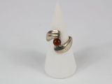 silver ring with a red stone in the middle of it on a white cone